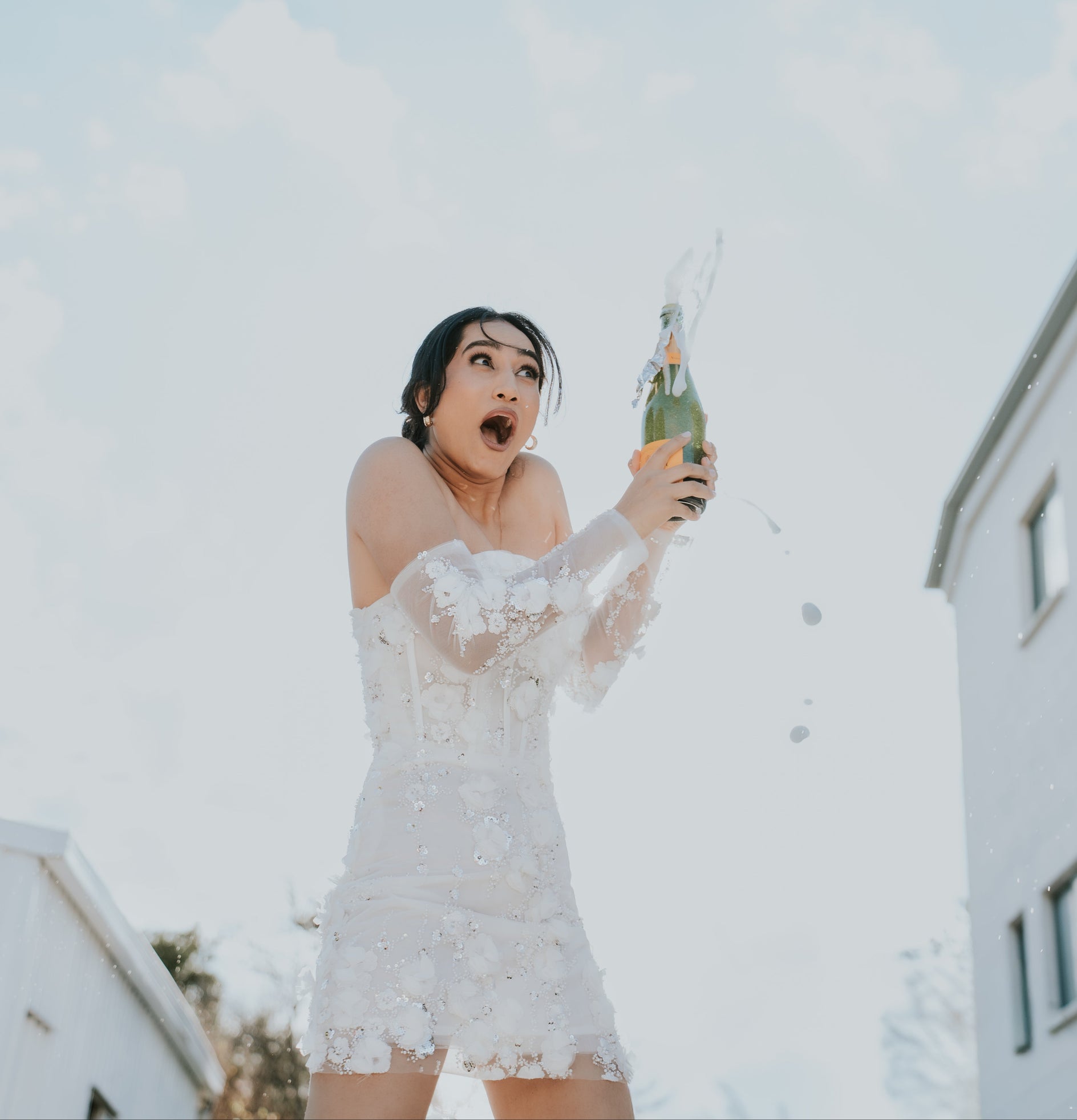 Woman in Saskia white lace dress with champagne
